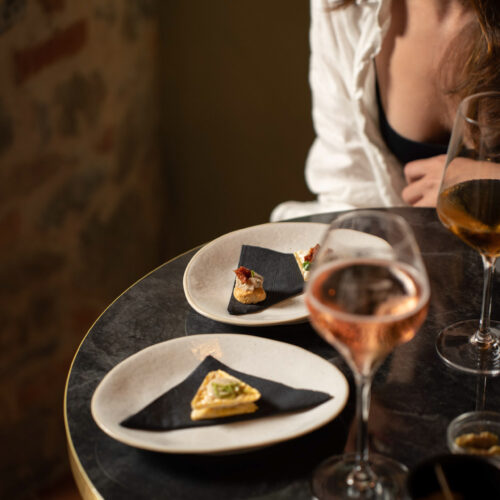 A joyful moment at Oratio Wine Bar & Library, with elegant appetizers and a glass of rosé wine.