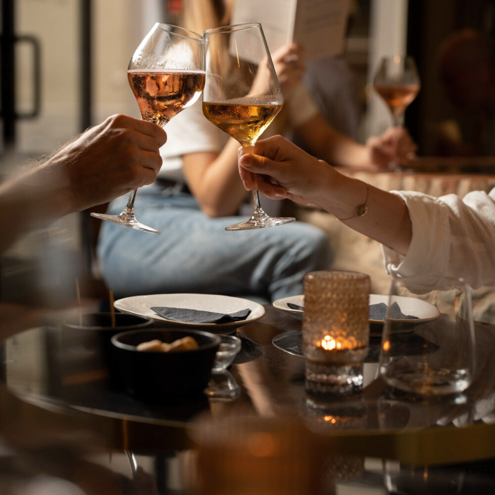 Elegant wine toast with sparkling rosé at Oratio Wine Bar & Library in Florence, with a cozy candlelit atmosphere.