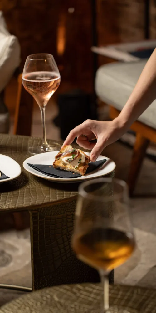 Elegant wine and food pairing at Oratio Wine Bar & Library, featuring a gourmet appetizer and a glass of sparkling rosé.